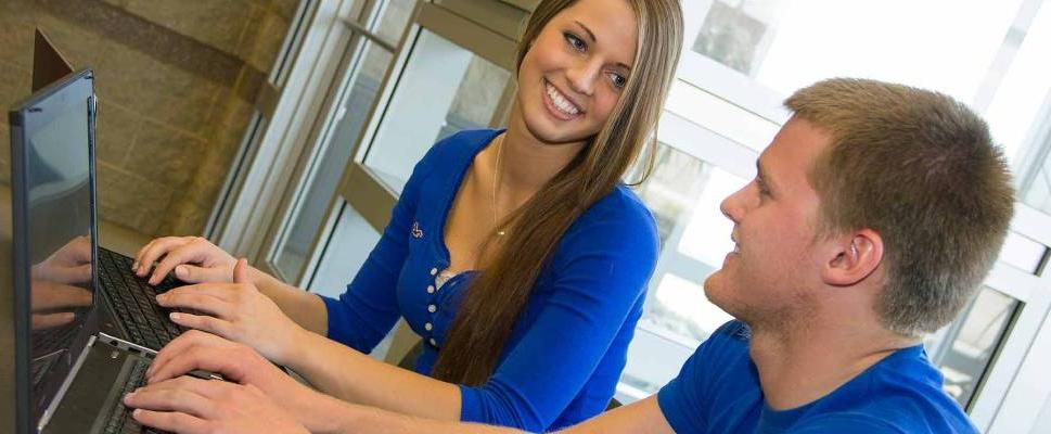 Two students smiling with open laptop